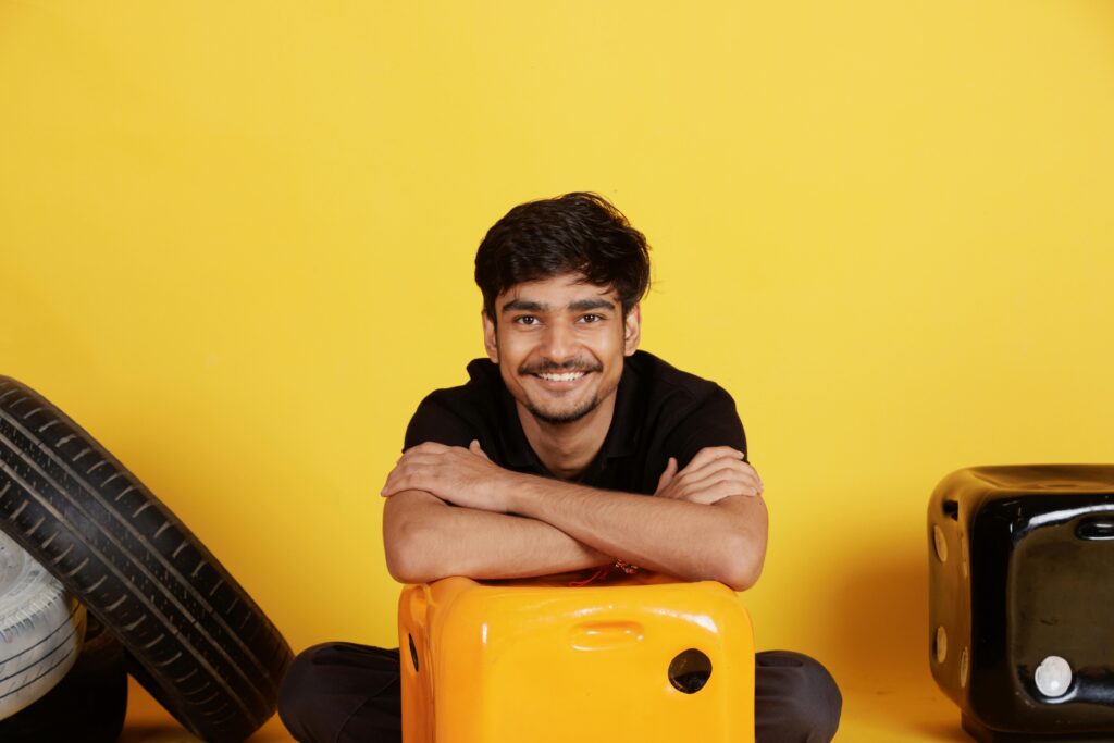 Smiling young man in casual wear posing with colorful props indoors, radiating positivity and joy.